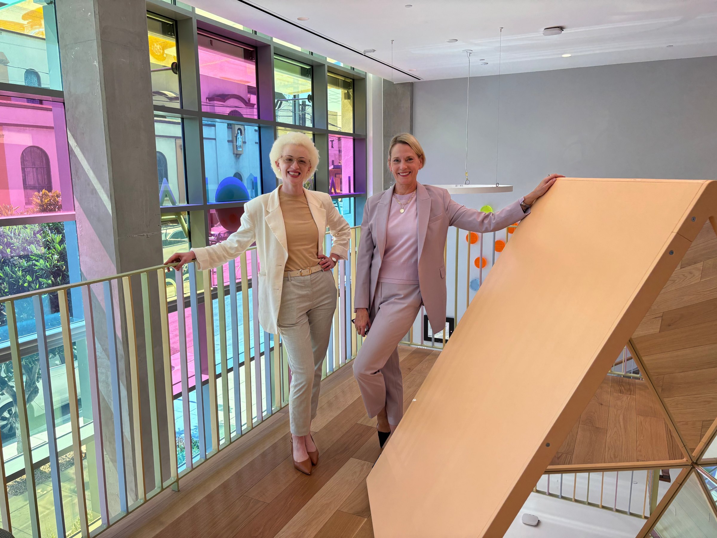 Two members of the admissions team standing by a railing in front of colored glass windows